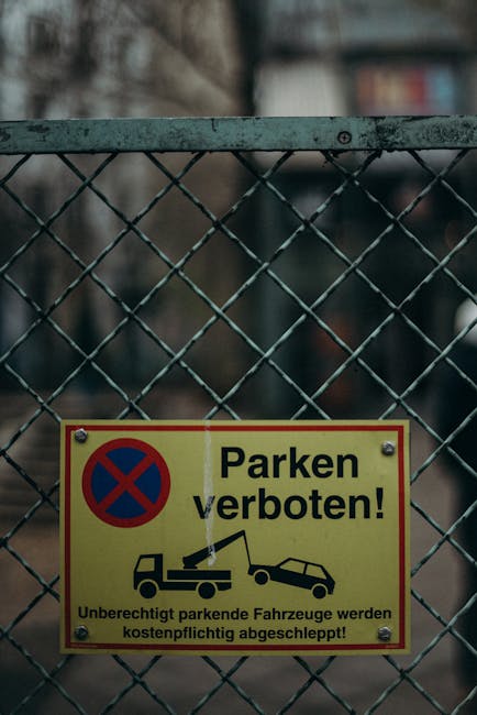 A weathered red and white parking suspension sign attached to a wire fence overgrown with dry, tangled branches. The sign reads 'Private Parking Permit Only' and indicates restrictions against unautho